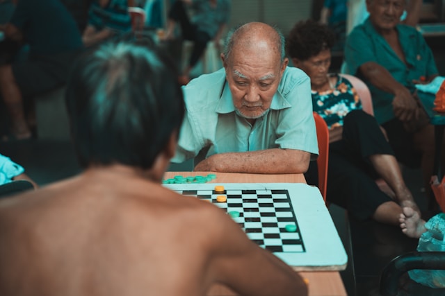 A pair of elderly friends playing a game of checkers